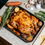 Poulet rôti avec peau croustillante et légumes racines, accompagné de romarin et ail sur planche à découper