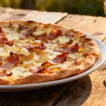 Tarte flambée traditionnelle avec oignons caramélisés, lardons et crème sur table en bois, accompagnée d'un verre de riesling